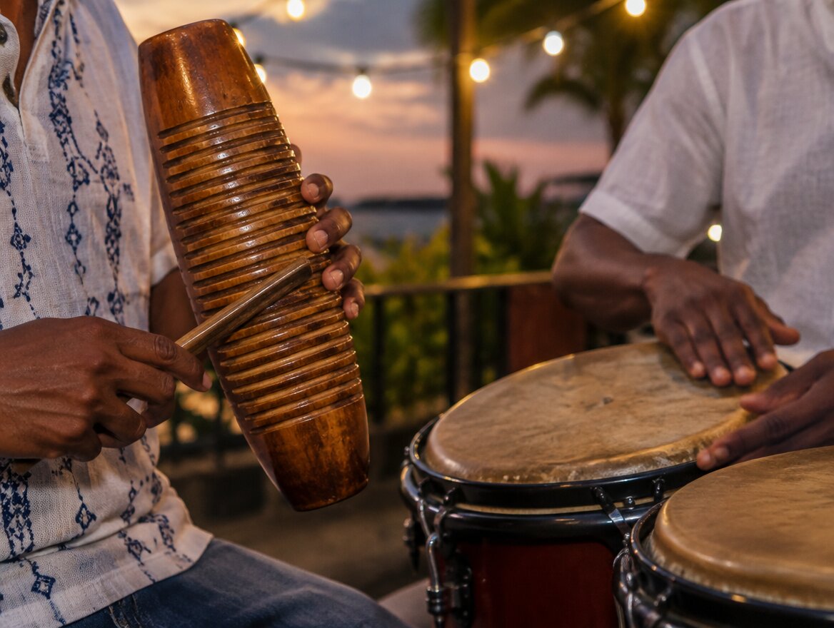 Manos tocando güira y bongó en un ambiente cultural dominicano al atardecer