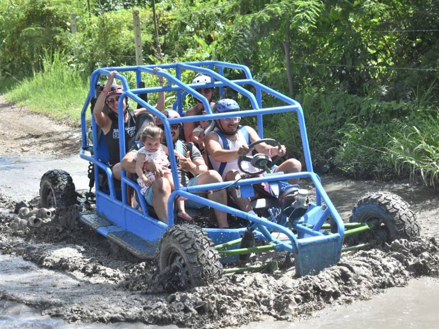 Family riding a buggy through a muddy trail on a Dominican excursion